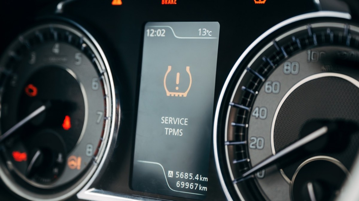 Dashboard showing a flashing TPMS warning light while a car is being driven