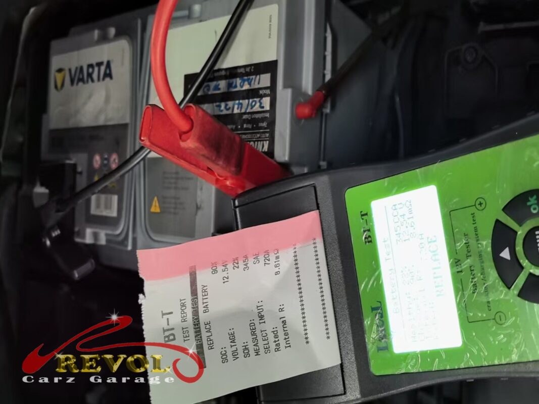 Car battery tester connected to battery terminals showing replace result while engine runs