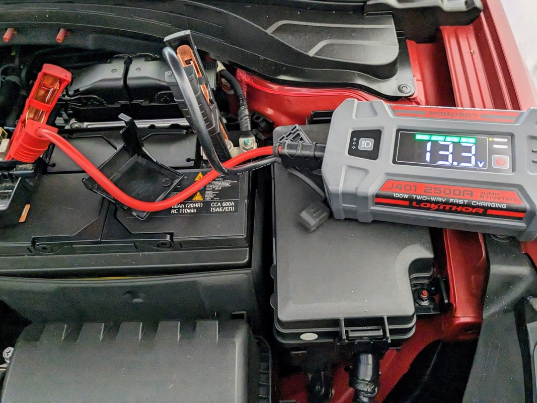 Diagram of a portable jump starter connected to a car battery showing voltage and current flow.