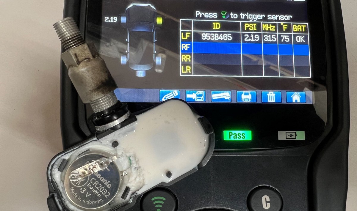 Technician using TPMS tool to relearn sensor after battery replacement or new sensor installation.