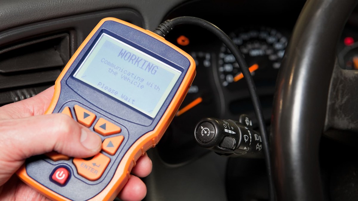 OBD2 scanner connected to a car's diagnostic port showing an emission system code
